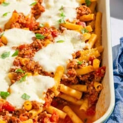Baked ziti with one serving removed in a baking dish.