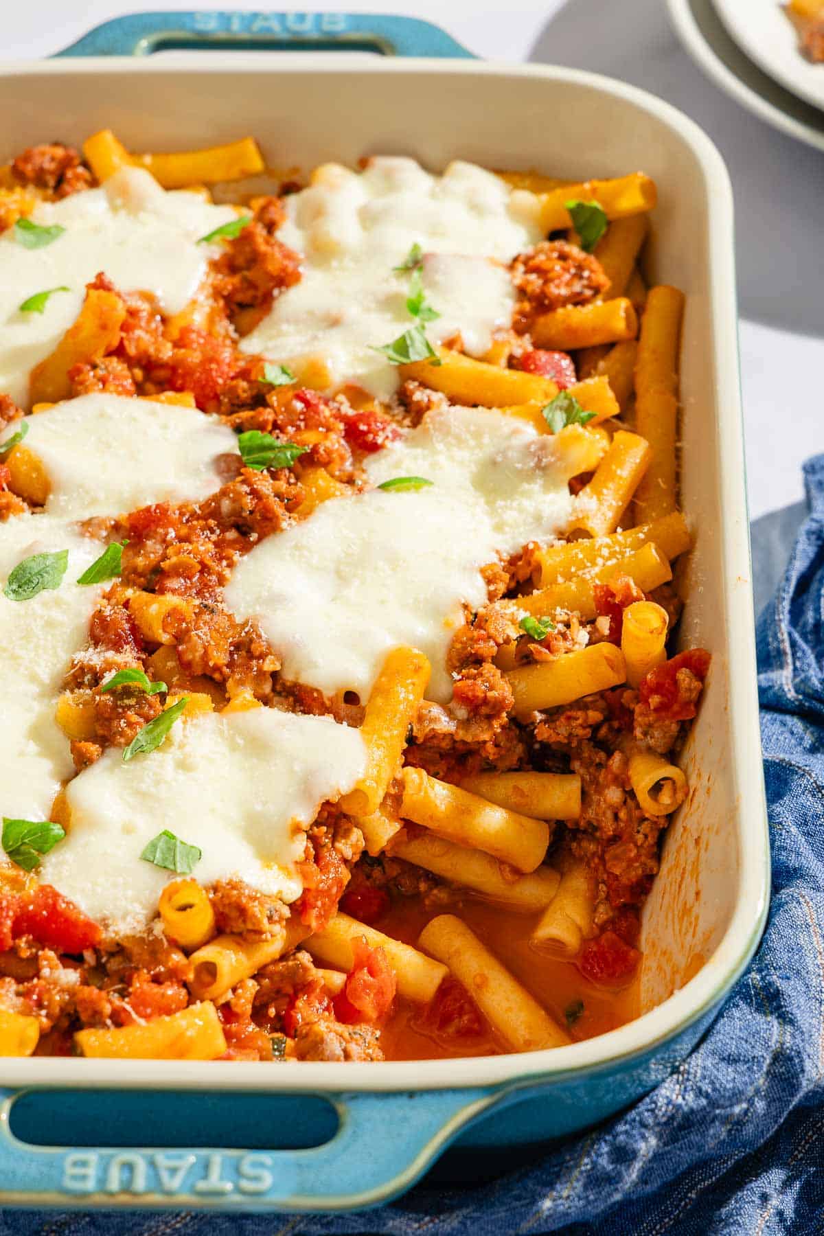 Baked ziti with one serving removed in a baking dish.