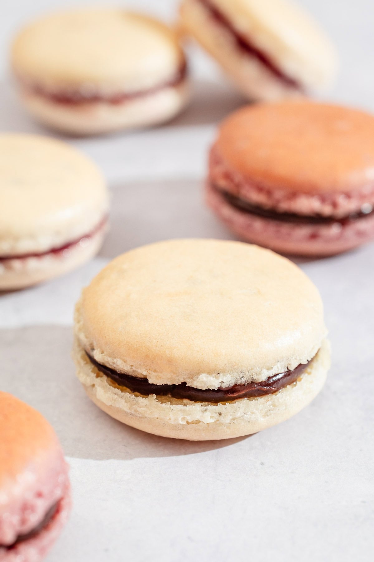 Several macarons on a parchment lined sheet pan.