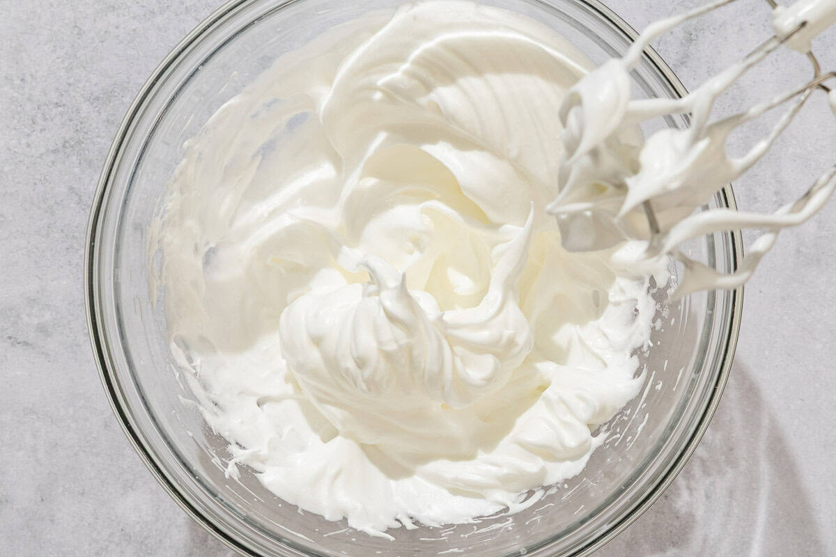 The meringue for the macarons in a bowl next to a hand mixture.