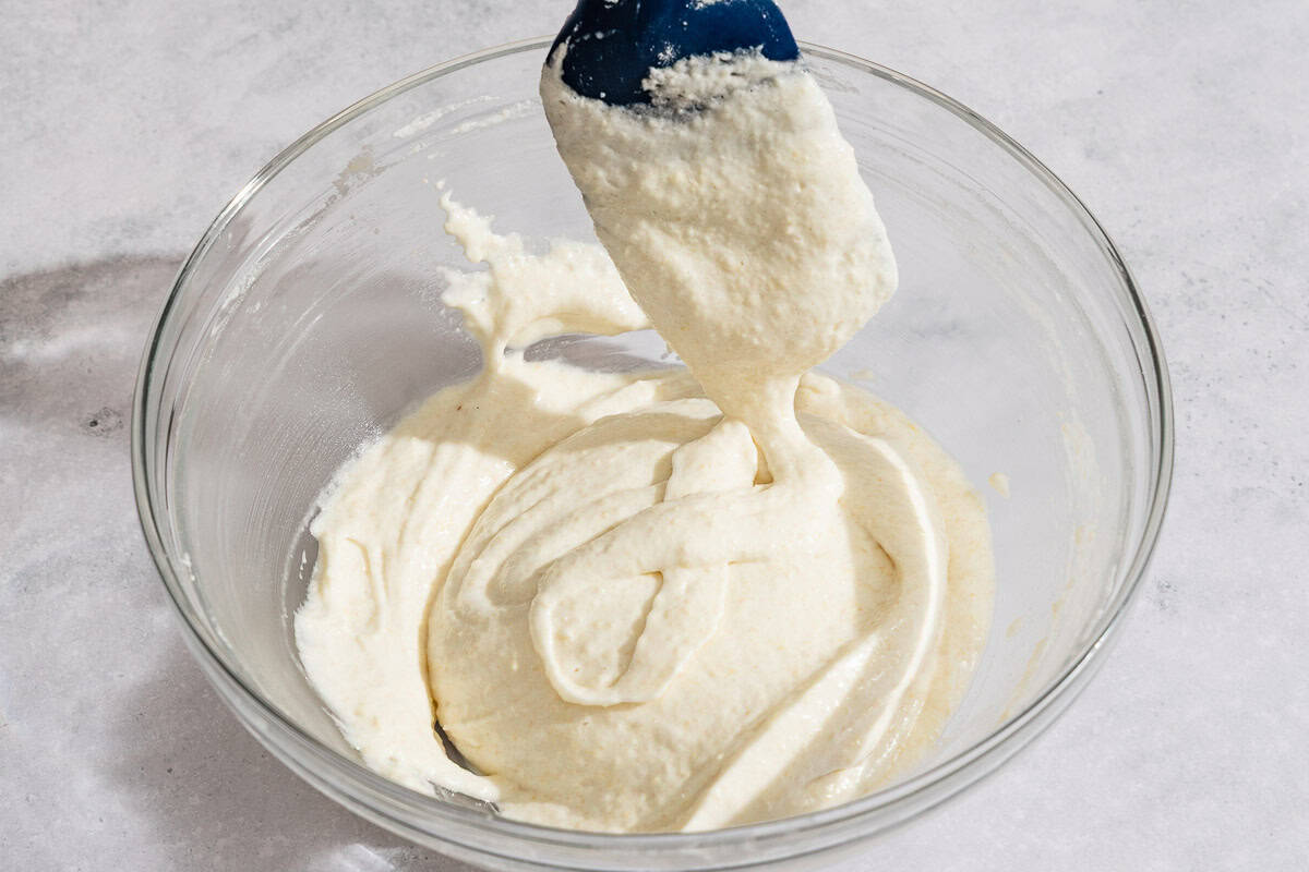 The macaronage for the macarons being gently mixed in a bowl with a spatula.