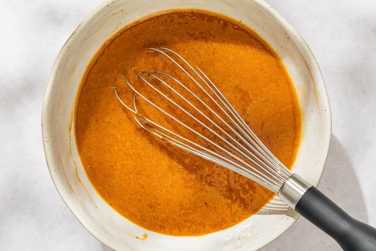 The wet ingredients for the persimmon bread recipe in a bowl with whisk.
