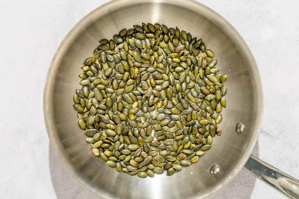 Pepitas being toasted in a skillet.