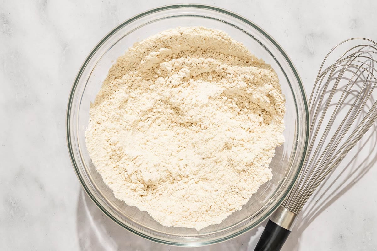 The dry ingredients for the pumpkin bread in a bowl next to a whisk.