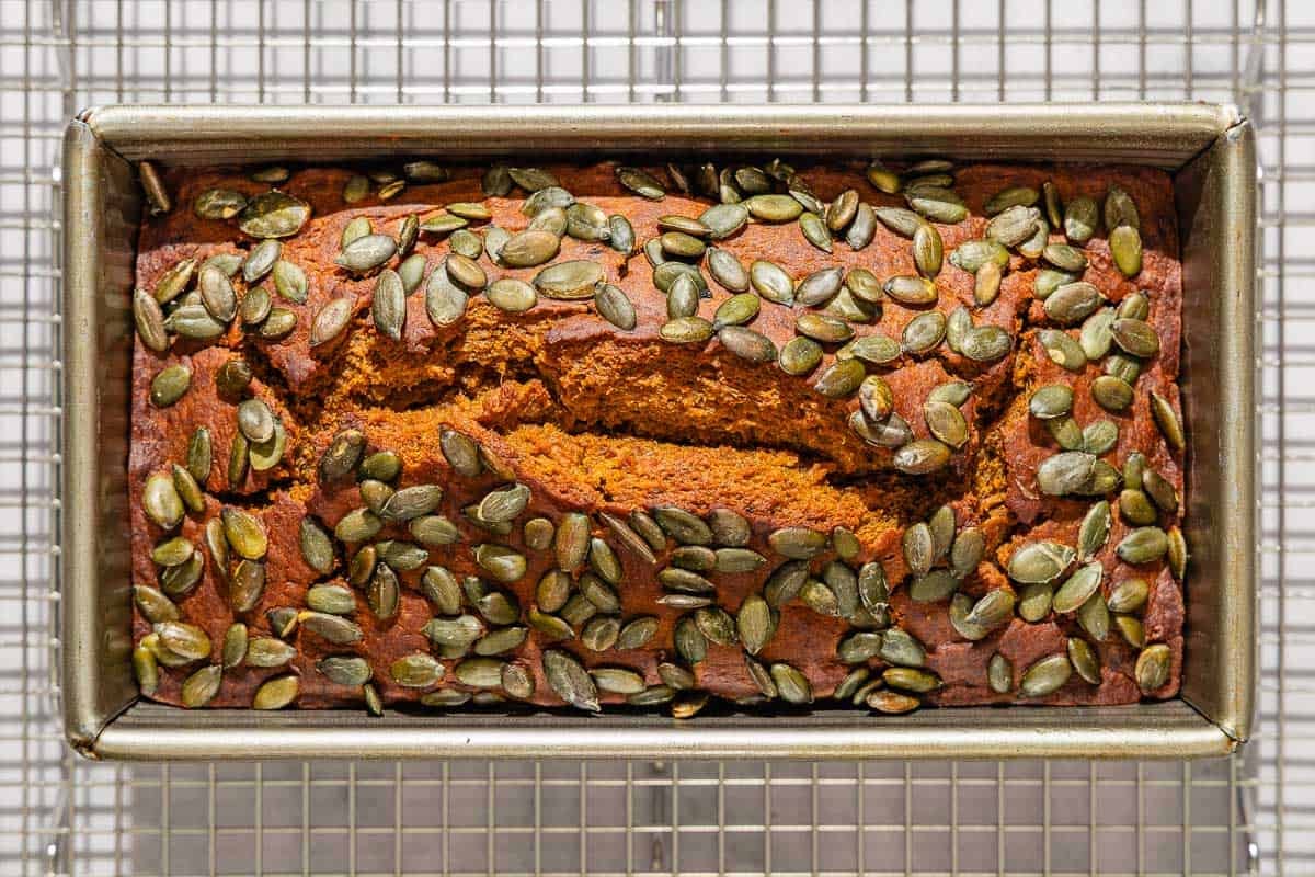 An overhead photo of the pumpkin bread in a loaf pan on a wire rack.