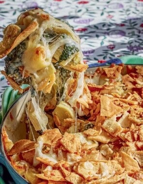 A spoonful of the spinach artichoke pasta being held over the rest of the pasta in a skillet.