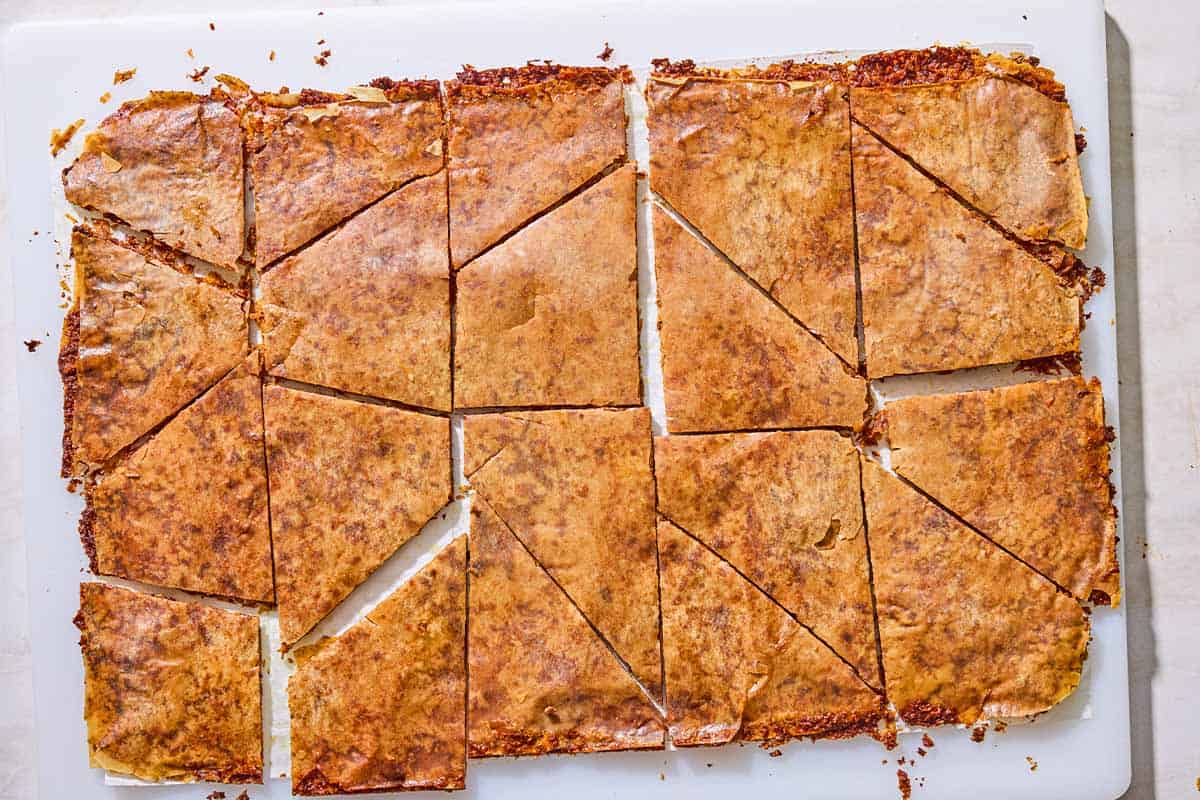 Broken pieces of baklava bark on a cutting board.