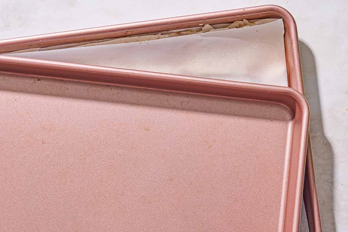 a parchment lined sheet pan under an unlined sheet pan.