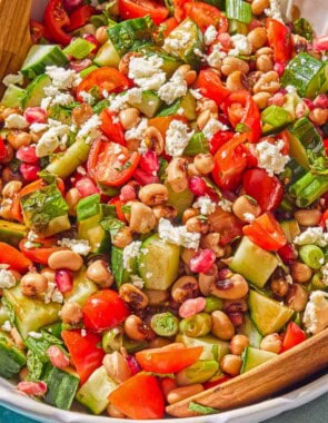 The black eyed pea salad in a bowl with wooden serving utensils.