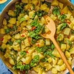 The blitva in a skillet with a wooden spoon. Next to this is a small bowl of Calabrian chilies.