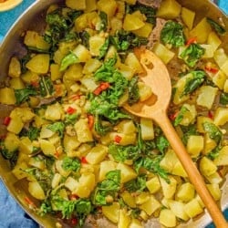 The blitva in a skillet with a wooden spoon. Next to this is a small bowl of Calabrian chilies.