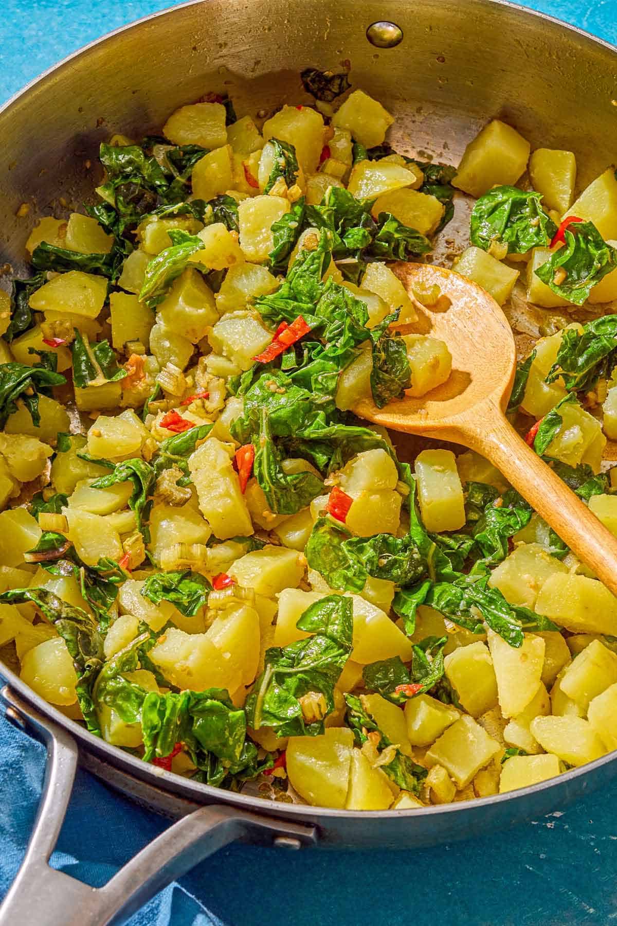 The blitva in a skillet with a wooden spoon.