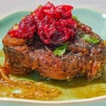 A serving of the braised lamb chops with cranberry harissa in a shallow bowl.