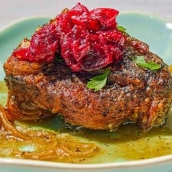 A serving of the braised lamb chops with cranberry harissa in a shallow bowl.