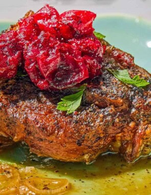 A close up of a serving of the braised lamb chops with cranberry harissa in a shallow bowl.