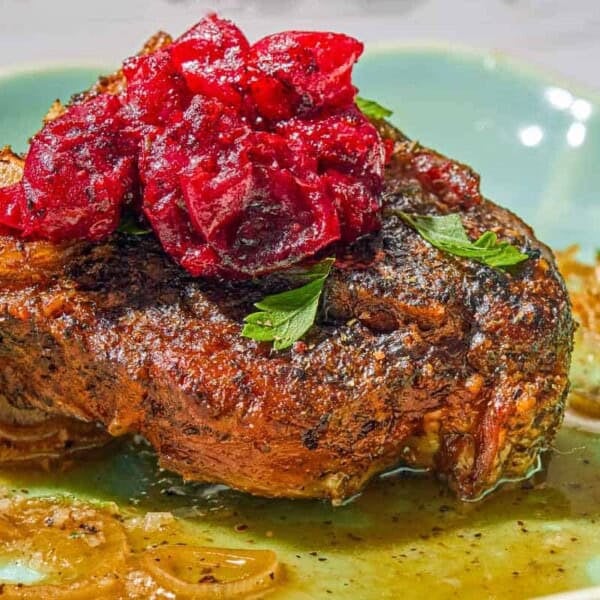 A close up of a serving of the braised lamb chops with cranberry harissa in a shallow bowl.