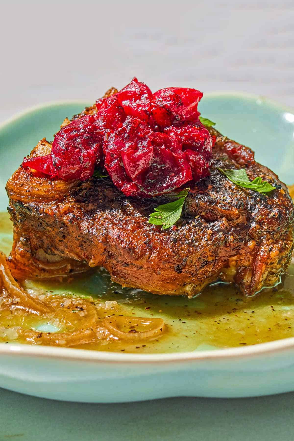 A serving of the braised lamb chops with cranberry harissa in a shallow bowl.