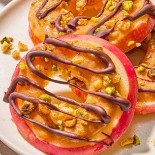 A close up of 3 caramel apple slices on a plate.