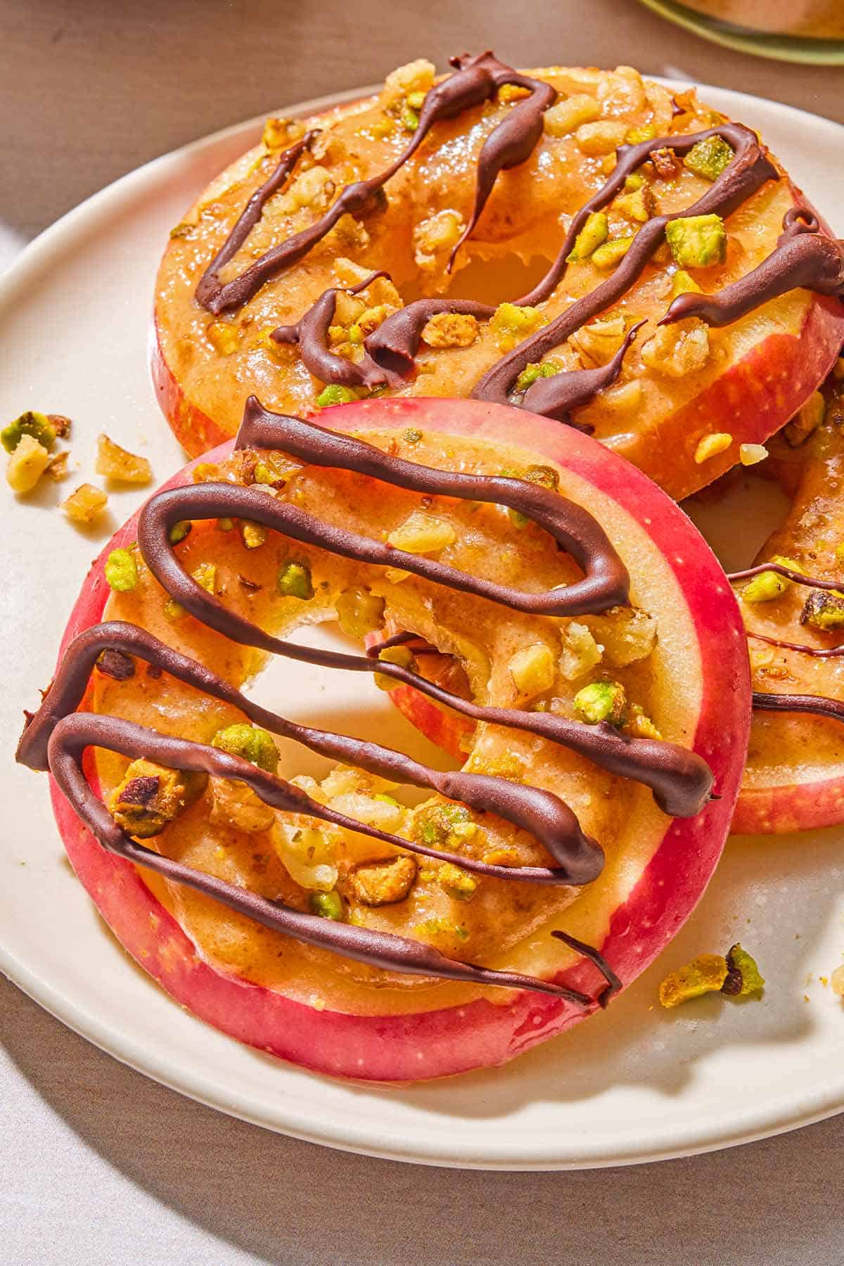 A close up of 3 caramel apple slices on a plate.