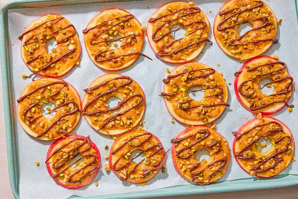 Several caramel apple slices spread evenly on a parchment lined sheet pan.