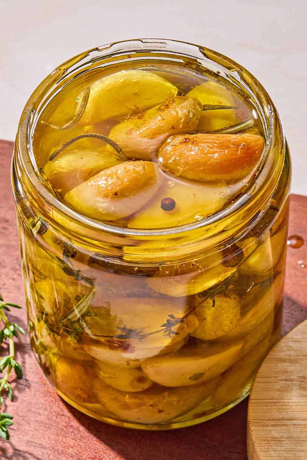 Garlic confit in a jar on a wooden tray.