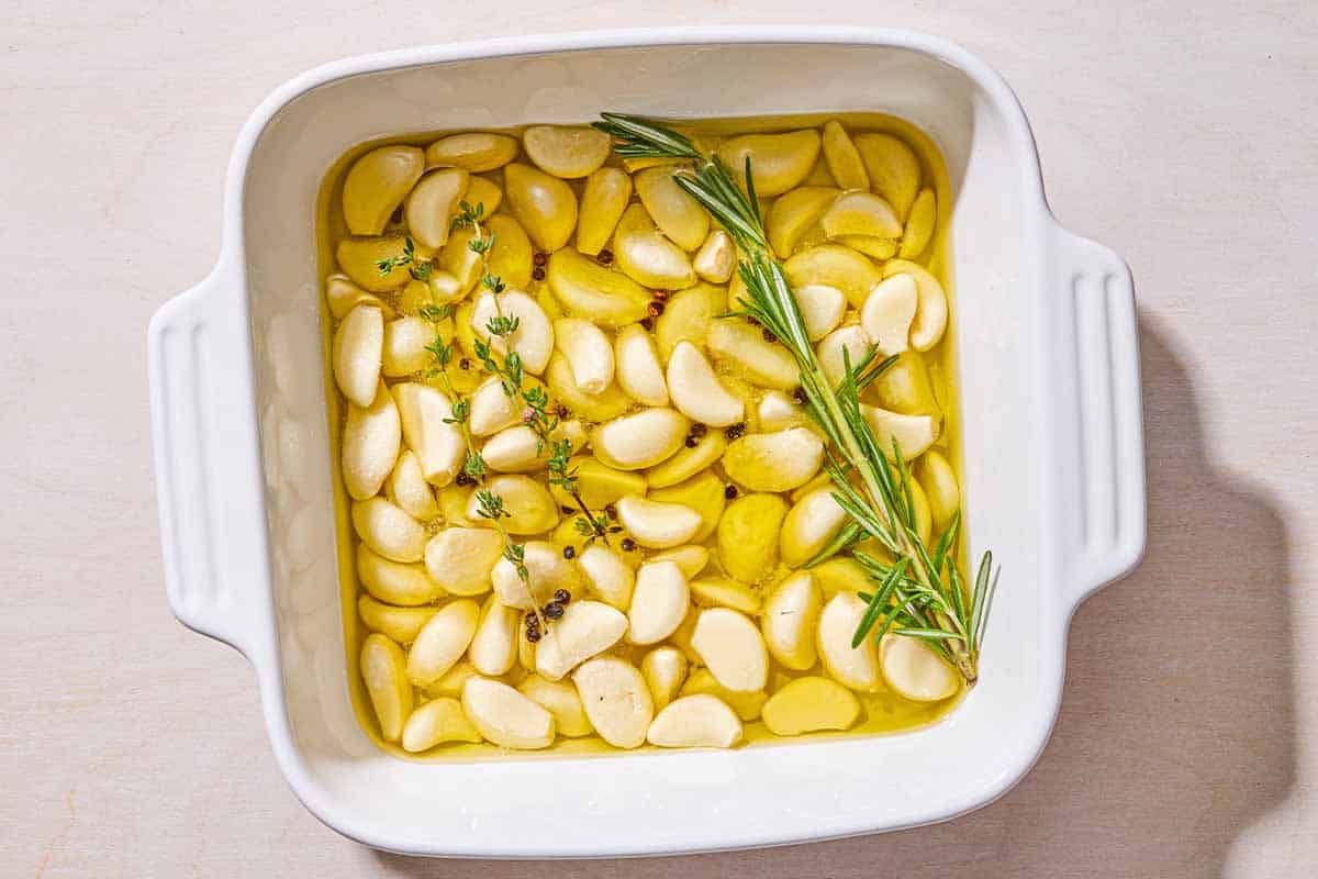 Un-roasted garlic confit in a square baking dish.