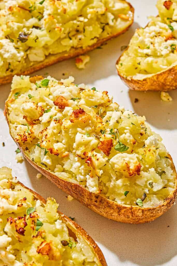 A close up of a twice baked potato surrounded by other twice baked potatoes.