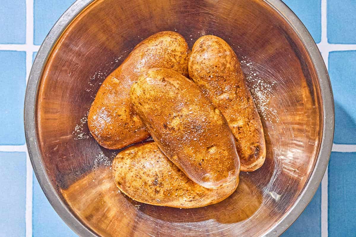 The oiled and salted potatoes in a large bowl.
