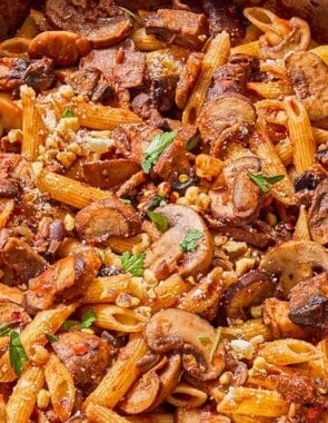 Mushroom pasta in a skillet with a wooden spoon.