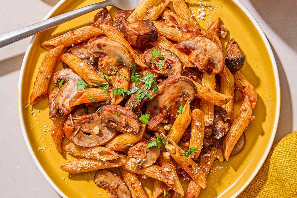 A serving of mushroom pasta on a plate with a fork.