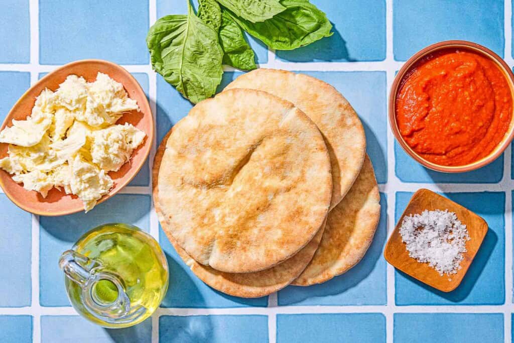 Ingredients for the pita pizza recipe including pita pockets, olive oil, marinara sauce, fresh mozzarella, salt and fresh basil.