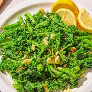 Broccoli rabe on a platter with lemon wedges.