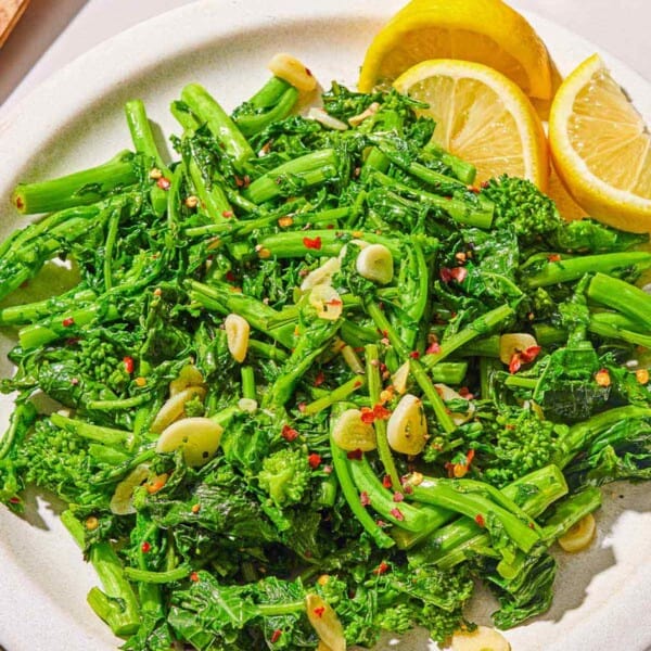 Broccoli rabe on a platter with lemon wedges.