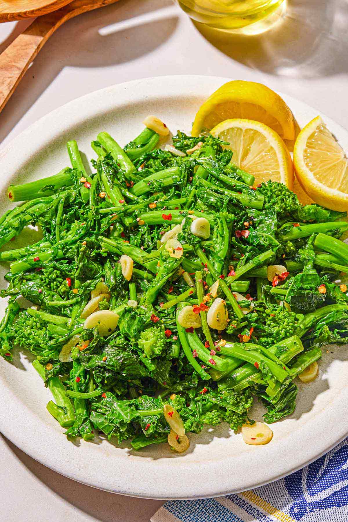 Broccoli rabe on a platter with lemon wedges.