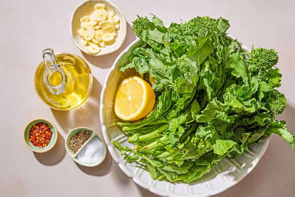 Ingredients for broccoli rabe including broccoli rabe, salt, garlic, olive oil, red pepper flakes, pepper and lemon.