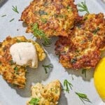 Three shrimp kofta on a plate with a lemon wedge. One has a dollop of tahini sauce on it.