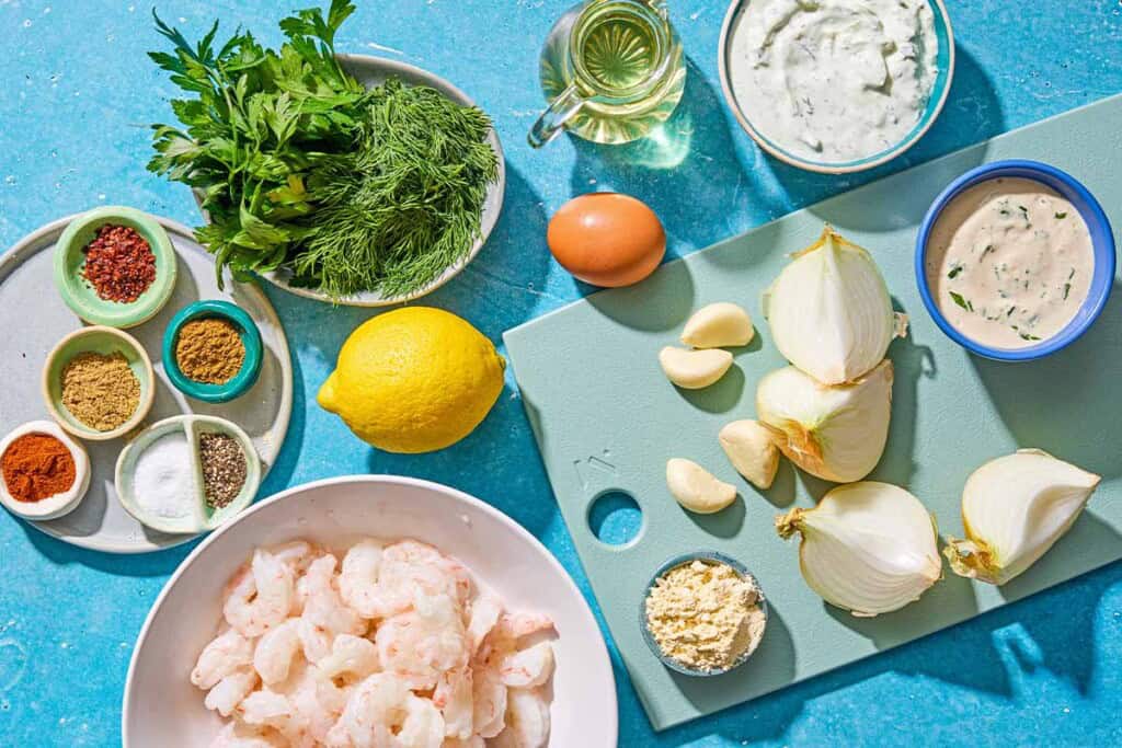 Ingredients for shrimp kofta including shrimp, onion, parsley, fill, garlic, salt, pepper, coriander, aleppo pepper, cumin, paprika, chickpea flour, egg, oil, lemon, tahini sauce, and tzatziki sauce.