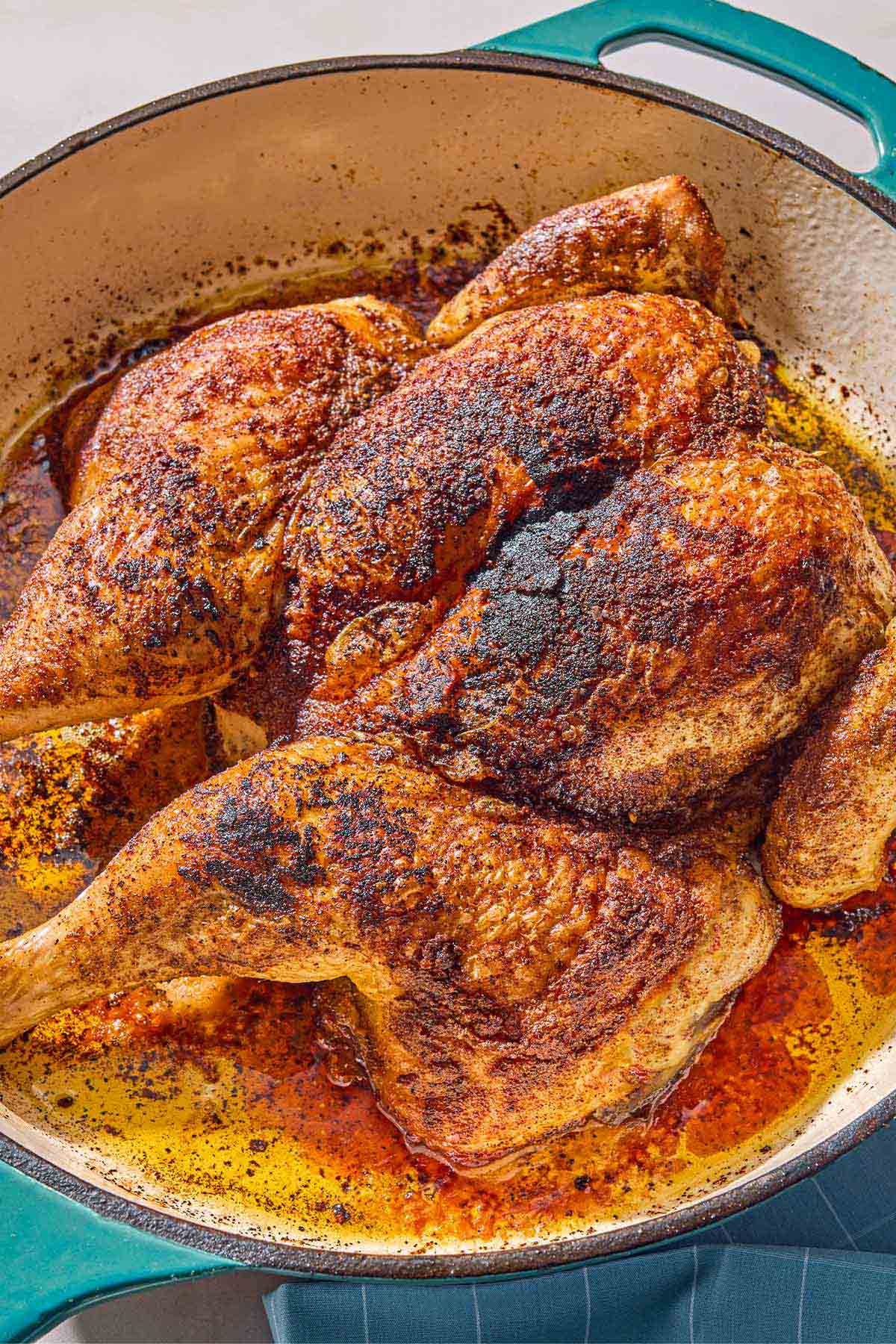 The whole cooked spatchcock chicken in a skillet.