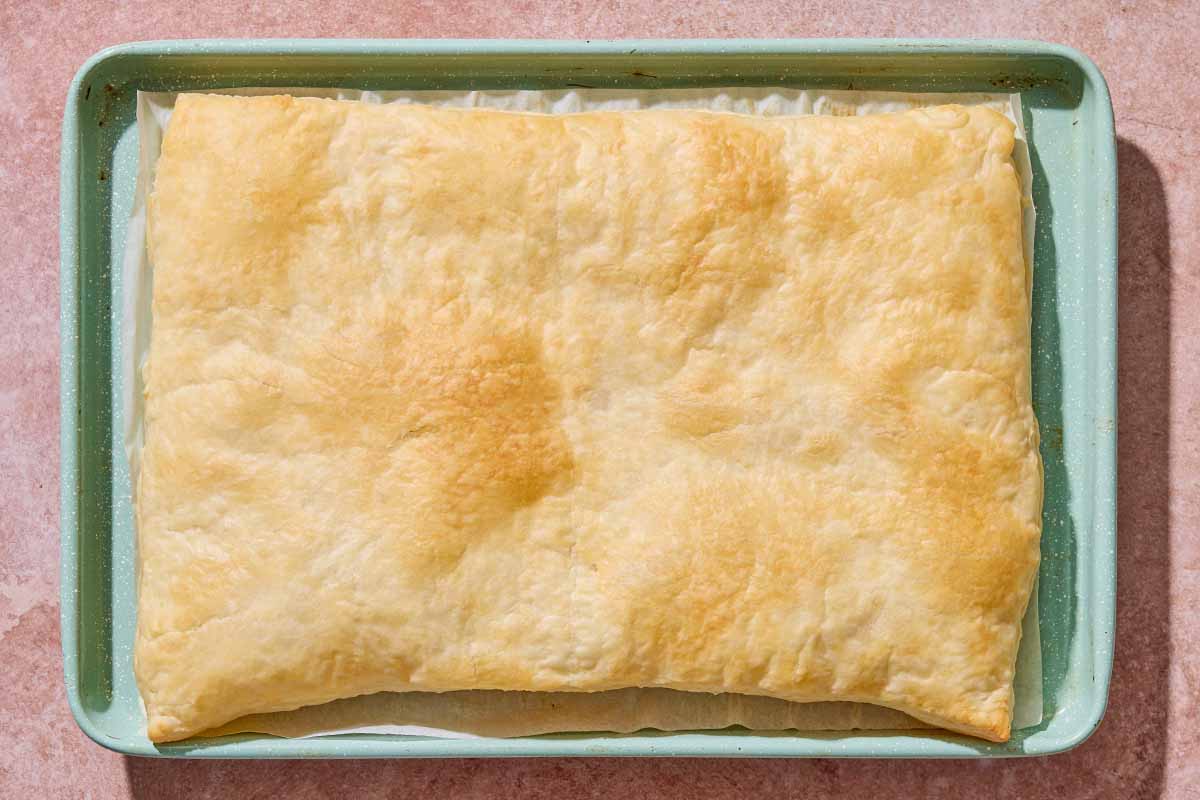 The baked puff pastry for the bread pudding on a parchment-lined sheet pan.