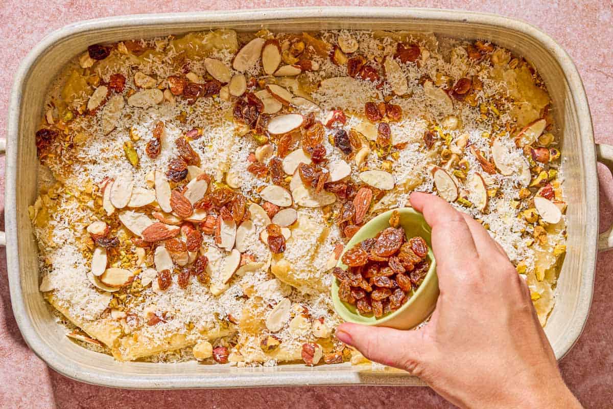 The raisins being placed on the unbaked bread pudding in the baking dish.