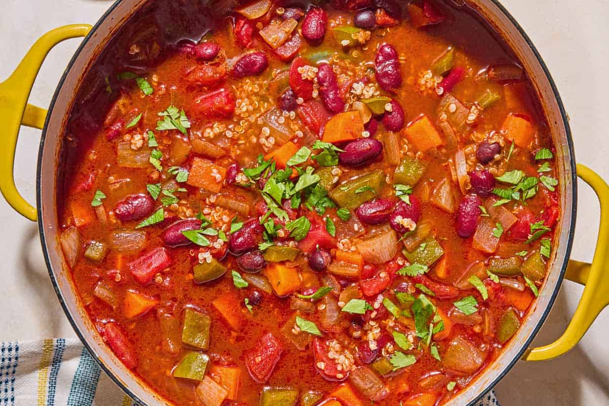 An overhead photo of vegan chili in a pot next to a kitchen towel.