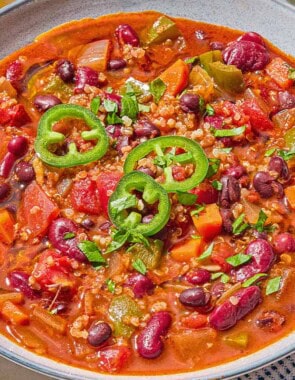 A bowl of vegan chili next to a cloth napkin with a spoon.