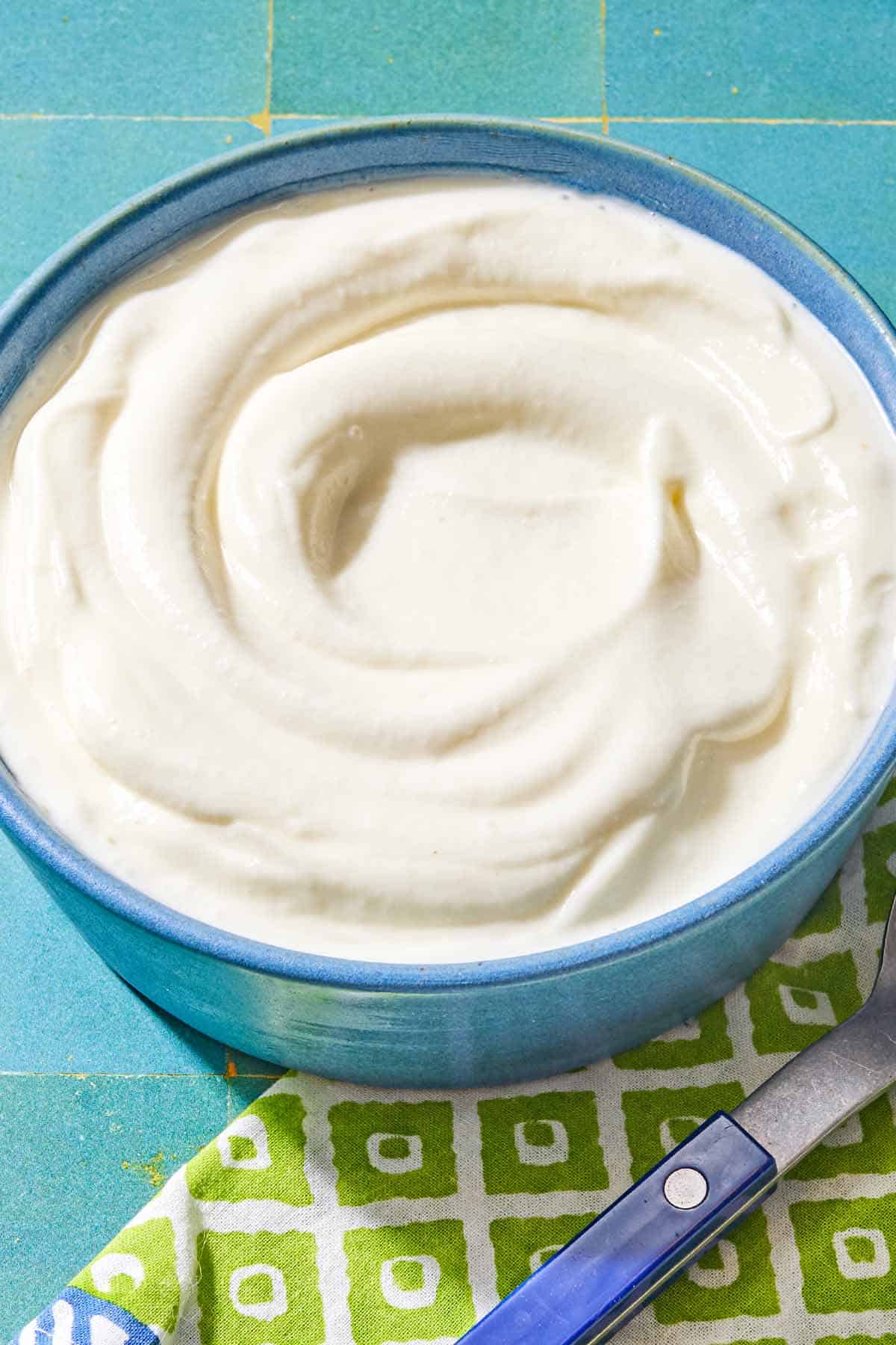 The toum recipe in a bowl. Next to this is a spoon on a napkin.