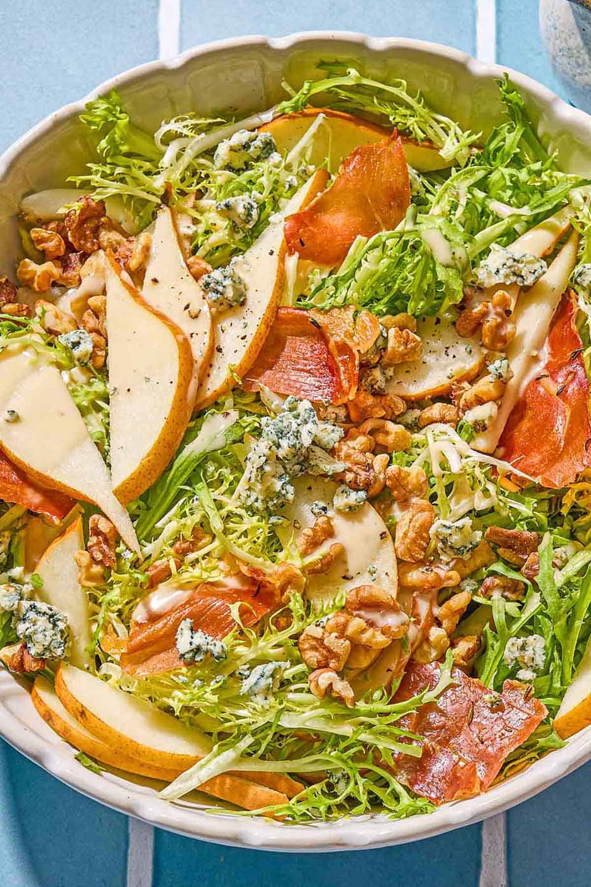 Frisee salad with pears and blue cheese in a serving bowl.
