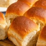A close up of dinner rolls on a wooden cutting board.