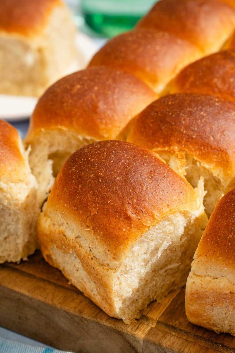 A close up of dinner rolls on a wooden cutting board.