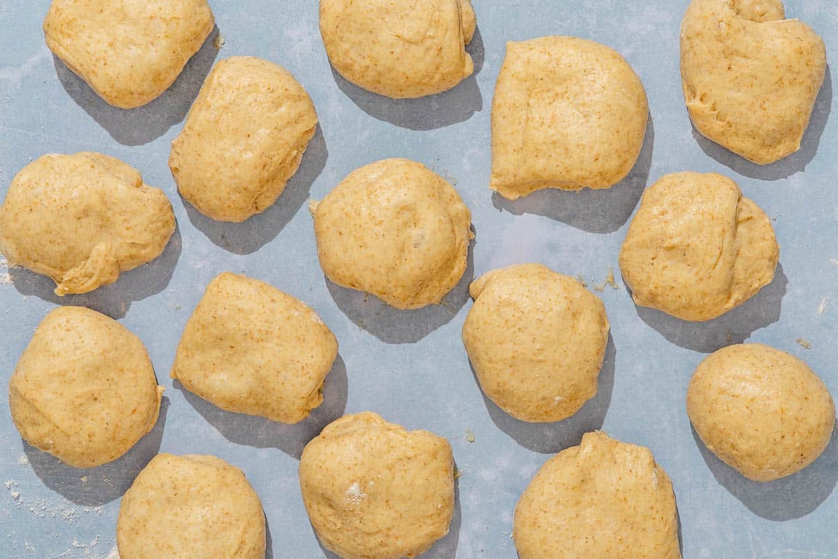 The dough balls for the dinner rolls on a piece of parchment paper.