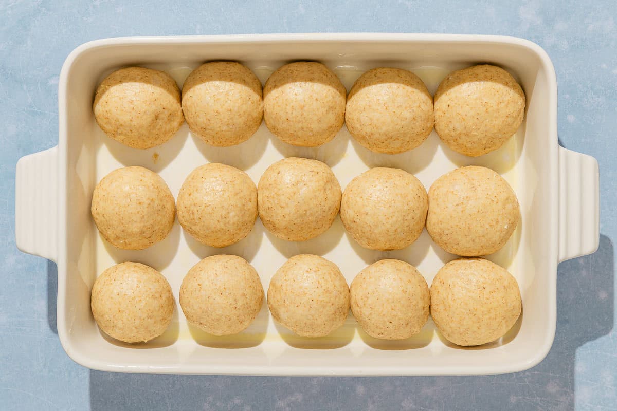 The dough balls for the dinner rolls in a baking dish.