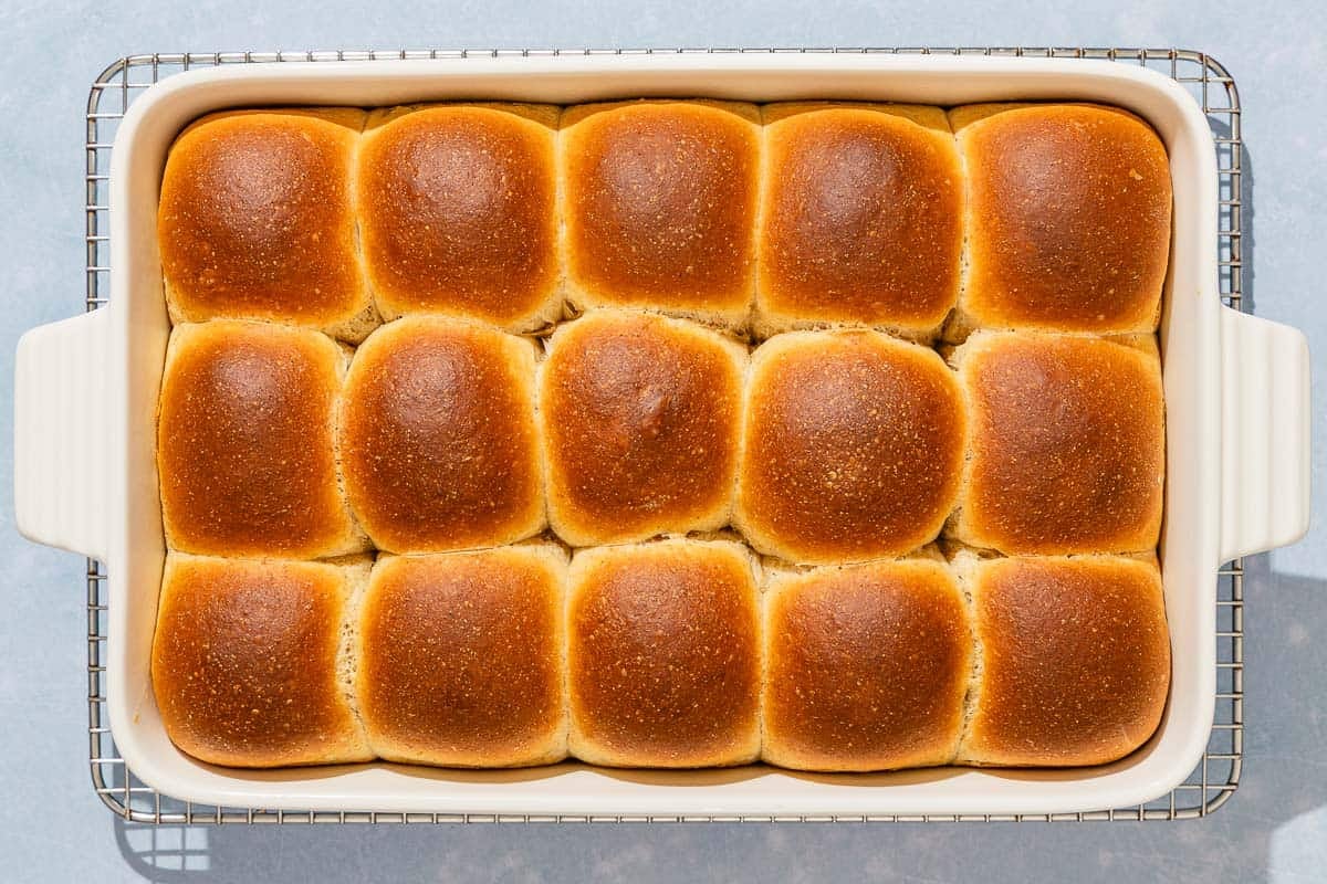 Baked dinner rolls in a baking dish cooling on a wire rack.