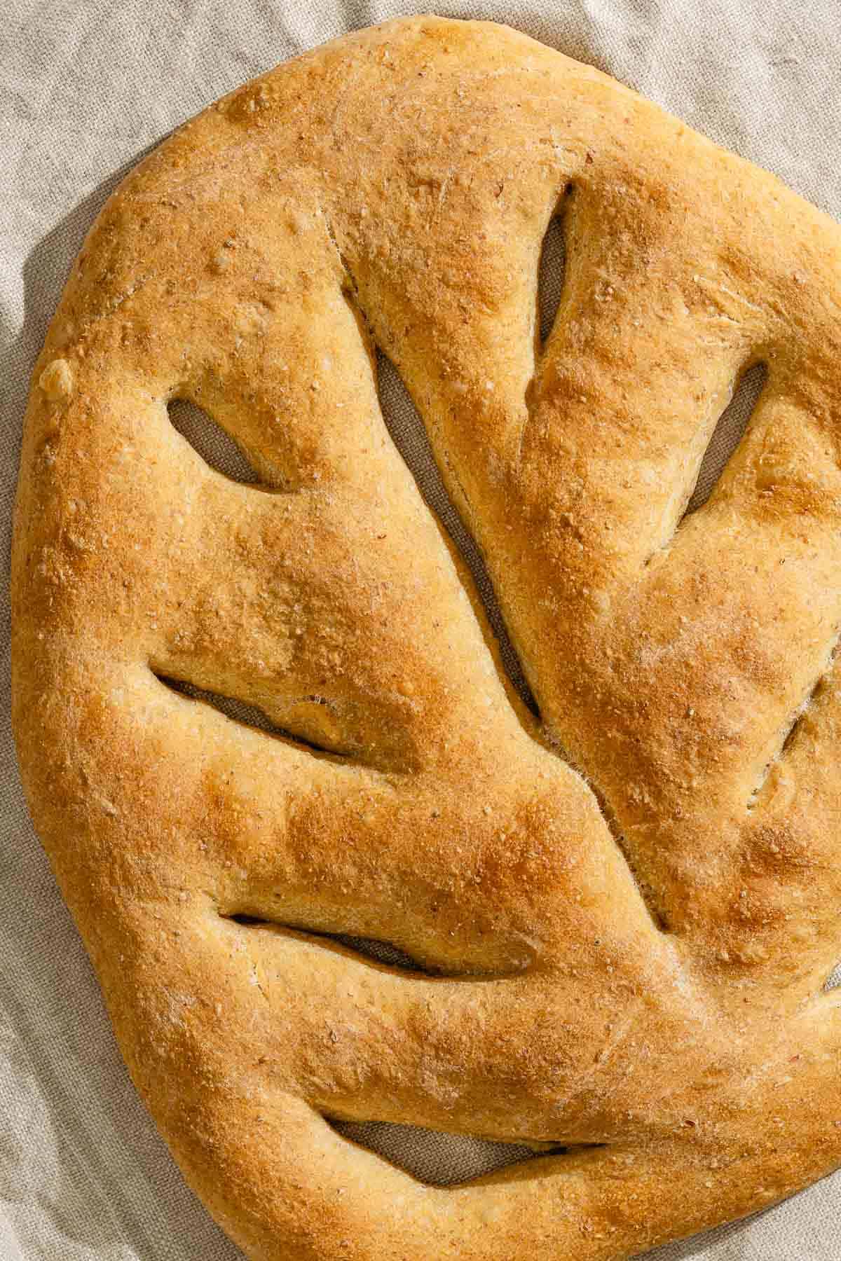 A close up of baked fougasse on a kitchen towel.